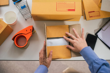 Top view of worker or seller packing product ecommerce shipping order box for dispatching. Preparing...