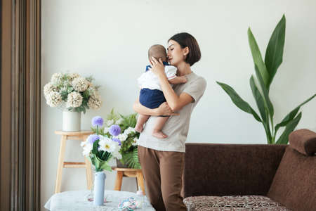 Asian mother holding love newborn, Mom holding newborn living at home. Motherâs Day concept.の写真素材