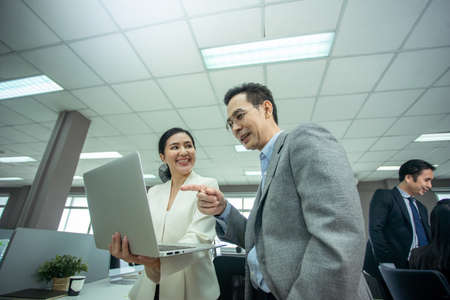 Businesswoman quick presenting work on computer laptop to businessman in office. Boss Asian man...