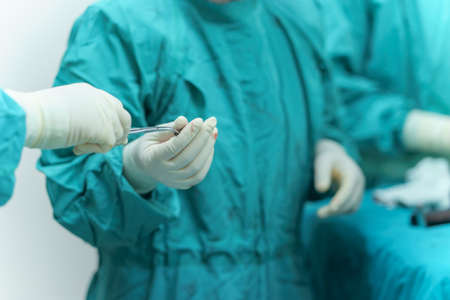 Team surgeon assistant send medical surgery instruments to Orthopedic doctor performing in operating...