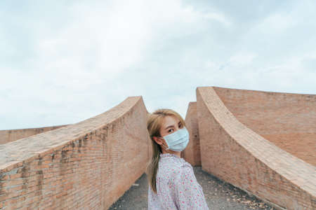Traveler Asian woman wearing medical face mask travel in coliseum architecture at Surin Thailand after recovered from pandemic virus. Travel trip new normal concept after pandemicの写真素材