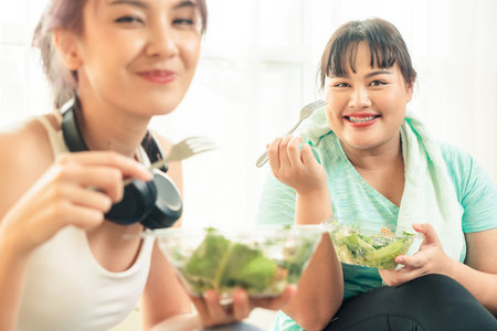Selective focus, Portrait Asian woman plus size in sportwear healthy eating vegetable salad together with her friend.の写真素材