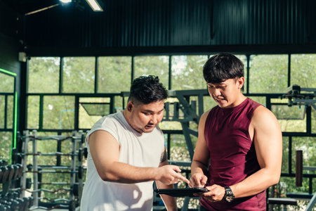 Asian man plus size and Coach discussion for progress and schedule in loss weight course training. Exercise with lose weight course concept.の写真素材