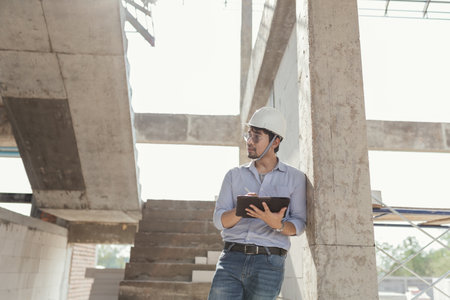 Asian man architect builder working in construction site. Civil Engineer working inspection progress in construction house project.の写真素材