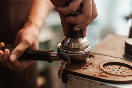 Closeup hand of barista preparation tampering ground coffee in portafilter for espresso machine. Coffee making concept.の写真素材