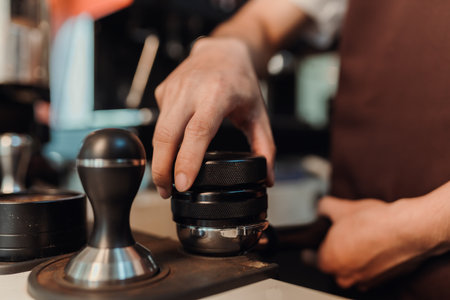 Closeup hand of barista preparation tampering ground coffee in portafilter for espresso machine. Coffee making concept.の写真素材