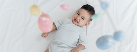 Top View, Adorable Asian Baby Boy, 5 Months Old, Smiling and Enjoy Playing with Crib Mobile in Home Playpen.の写真素材