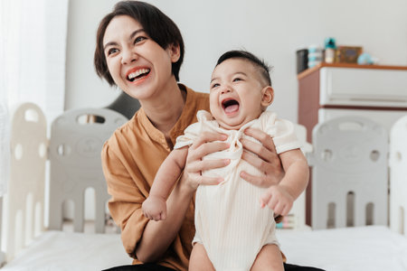Happiness Asian mother conference and playing with adorable her son looking at camera. Asian mom lifting and playing newborn baby. Happy asian family healthcare love together motherâs day concept.の写真素材