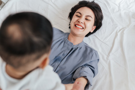 Top view, Happiness Asian mother laying on a bed and playing with her son. Together baby son playing with mother. Mother's day concept.の写真素材