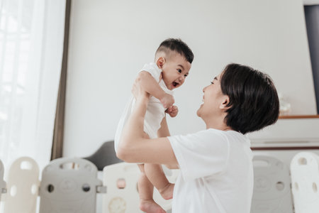 Adorable Asian baby have fun playing with mother. Asian mom lifting and playing newborn baby. Happy asian family healthcare love together motherâs day concept. Selective focus.の写真素材