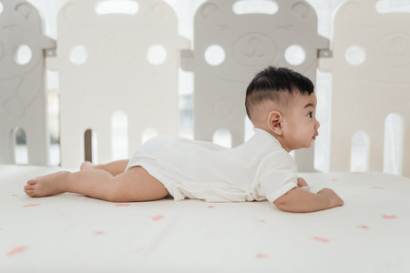 Asian baby start to crawling on a bed at home, Adorable development 5 months old. Baby healthcare hygiene concept.の写真素材