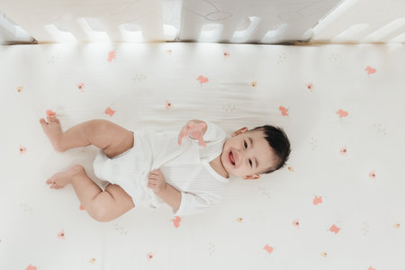 Adorable asian baby comfortable and good mood, Lying on a bed looking at camera. Baby healthcare hygiene concept.の写真素材