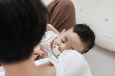 Top view, Young Asian mother holding her son baby sleeping on hand. Mom nurturing love newborn baby. Mom nursing baby. Happy asian family healthcare love together motherâs day concept.の写真素材