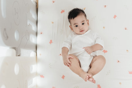 Adorable asian baby comfortable and good mood, Lying on a bed looking at camera. Baby healthcare hygiene concept.の写真素材