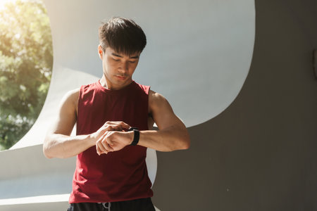 Asian man using app on smart watch for select music, Measure your heartbeat, and calories burned. Fitness, energy and athlete runner doing outdoor cardio workout for good health.の写真素材