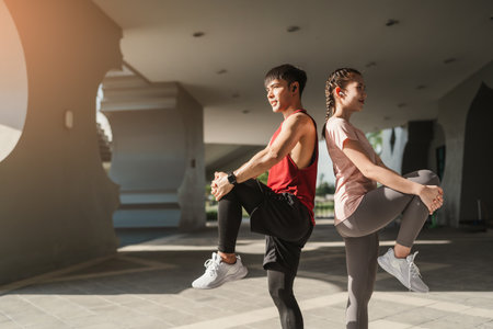 Young Asian couple stretching together before jogging exercise in urban area. Warming up for workout outdoor in the morning.の写真素材