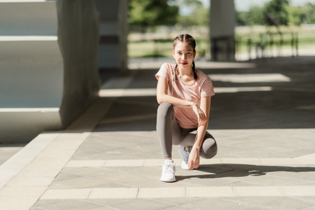 Young Asian woman tying shoelace on her running shoes. Preparation before jogging exercise. Fitness and sport activity. Healthy exercise concept.の写真素材