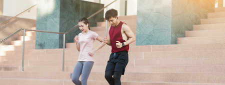 Asian young athlete man and woman in sportswear jogging exercise on the steps outdoor. Together young couple running outdoor in the morning. Healthy exercise concept.の写真素材