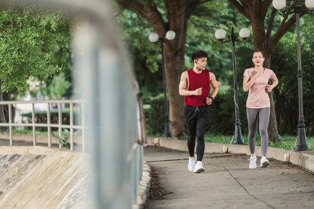 Two Asian young athlete man and woman in sportswear jogging exercise in park outdoor. Together young couple running outdoor in the morning. Healthy exercise concept.の写真素材