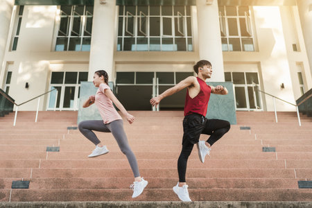 Full length Asian young athlete man and woman in sportswear jumping on the steps outdoor. Together young couple running outdoor in the morning. Healthy exercise concept.の写真素材