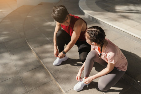 Preparation before jogging exercise. Together young Asian man and woman tying shoelace on her running shoes. Fitness and sport activity. Healthy exercise concept.の写真素材