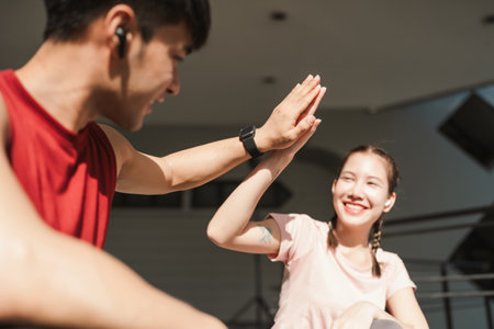 Motivated couple of runners celebrating cheerful and happy giving high five energetic and cheering. Sportive people training outdoors.の写真素材