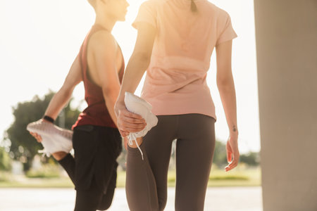 Young couple in sportswear doing stretching together before jogging exercise in urban area. Warming up for workout outdoor in the morning. Selective focus.の写真素材