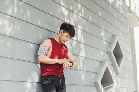 Asian man using app on smart watch for select music, Measure your heartbeat, and calories burned. Fitness, energy and athlete runner doing outdoor cardio workout for good health.の写真素材