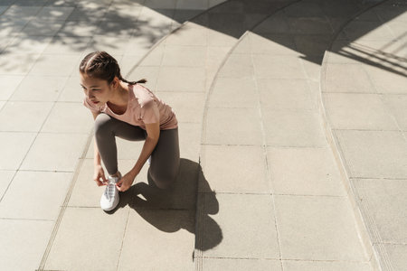 Young Asian woman tying shoelace on her running shoes. Preparation before jogging exercise. Fitness and sport activity. Healthy exercise concept.の写真素材
