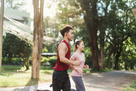 Two Asian young athlete man and woman in sportswear jogging exercise in park outdoor. Together young couple running outdoor under sunshine in the morning. Healthy exercise concept.の写真素材