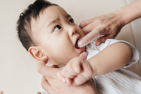 Cleaning Asian baby's mouth by brushing his teeth. Baby care, baby's first teeth. Closeup Shot, Embracing the Concept of Baby Care.の写真素材