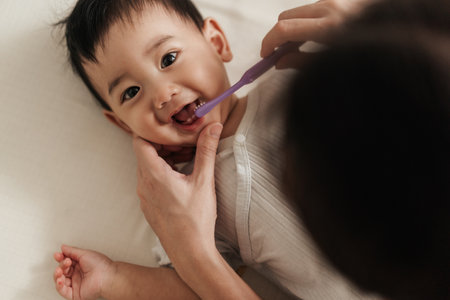 Cute Asian boy baby cleaning mouth with brushing his teeth by mother. Baby care, baby's first teeth....
