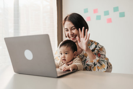 Happiness together, A little boy Asian baby and mother use computer laptop with video calls with father or long-distance relatives. Tech-Fueled Family Love Concept.の写真素材