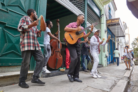 Cheerful street musicians playing on a street outdoors and people watching on a terrace in Cubaのeditorial素材