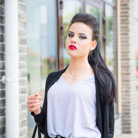 A beautiful girl with a stern look on the background of the glass buildingの写真素材