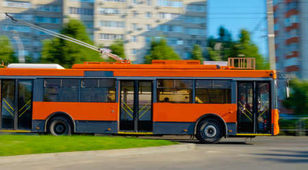 beautiful new orange trolleybus moving early in the morning on the beautiful roadの写真素材