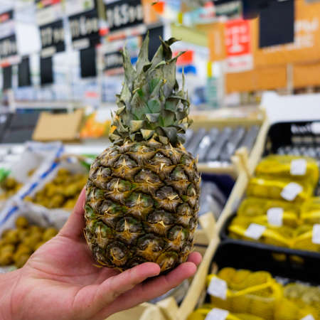 man holding fresh pineapple in a shopping centerの写真素材