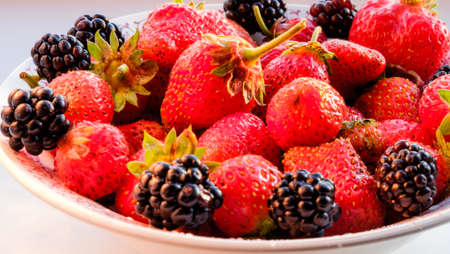 Mix of fresh berries in a basket on rustic wooden backgroundの写真素材