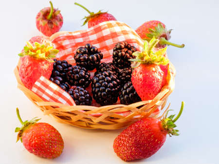 Mix of fresh berries in a basket on rustic wooden backgroundの写真素材