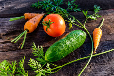 Healthy food concept. Frame of vegetables. Tomatoes Coeur de Boeuf, cucumbers and carrots on a wooden backgroundの写真素材