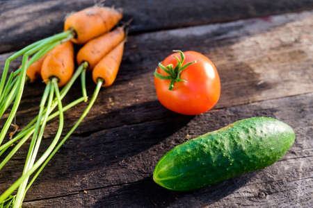 Healthy food concept. Frame of vegetables. Tomatoes Coeur de Boeuf, cucumbers and carrots on a wooden backgroundの写真素材