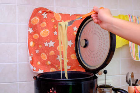 She interferes with delicious spaghetti multivarka in the home kitchen.の写真素材