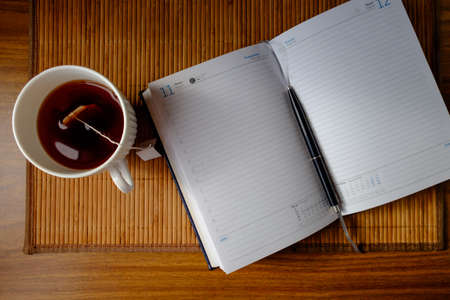 Delicious tea in a white shirt and a nice notebook early in the morning before work.の写真素材