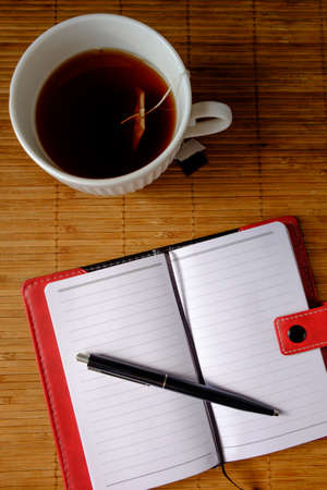 Delicious tea in a white shirt and a nice notebook early in the morning before work.の写真素材