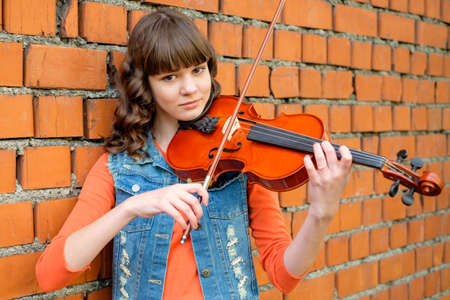 Beautiful young girl walking and playing the violin good music.の写真素材