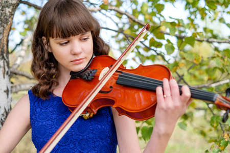 Beautiful young girl walking and playing the violin good music.の写真素材