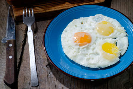 fried eggs in an old pan on wooden boards and near all the bread in retro styleの写真素材