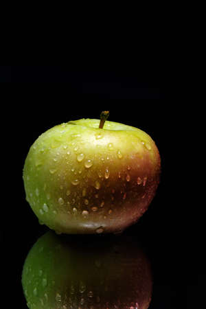 two-color, fresh, tasty apple on a black background with reflection.の写真素材
