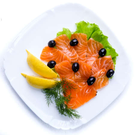 A dish of fresh fish decorated with chopped vegetables on a white plate.の写真素材