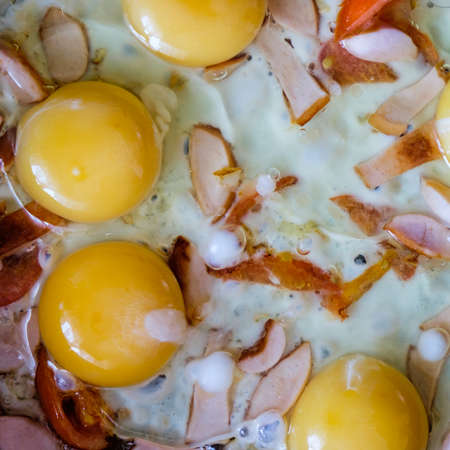 Cooking a delicious omelet in a pan, and the meal on a blue plate on a black table.の写真素材